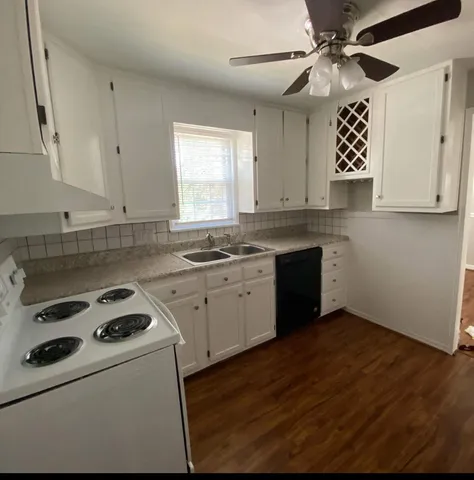 a kitchen with a stove cabinets and wooden floor