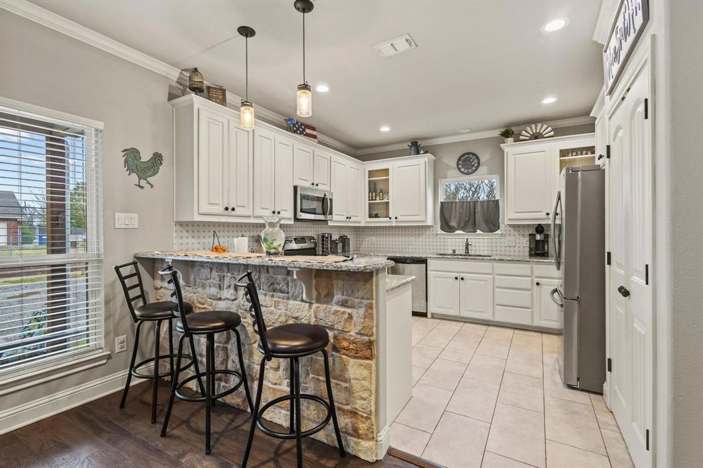293 Redden Road Van Alstyne, TX 75495 - Photo 12 of 40 a kitchen with stainless steel appliances kitchen island granite countertop a table chairs sink and cabinets