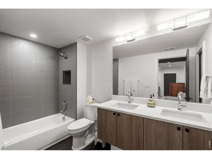 a bathroom with a double vanity sink toilet mirror and bathtub