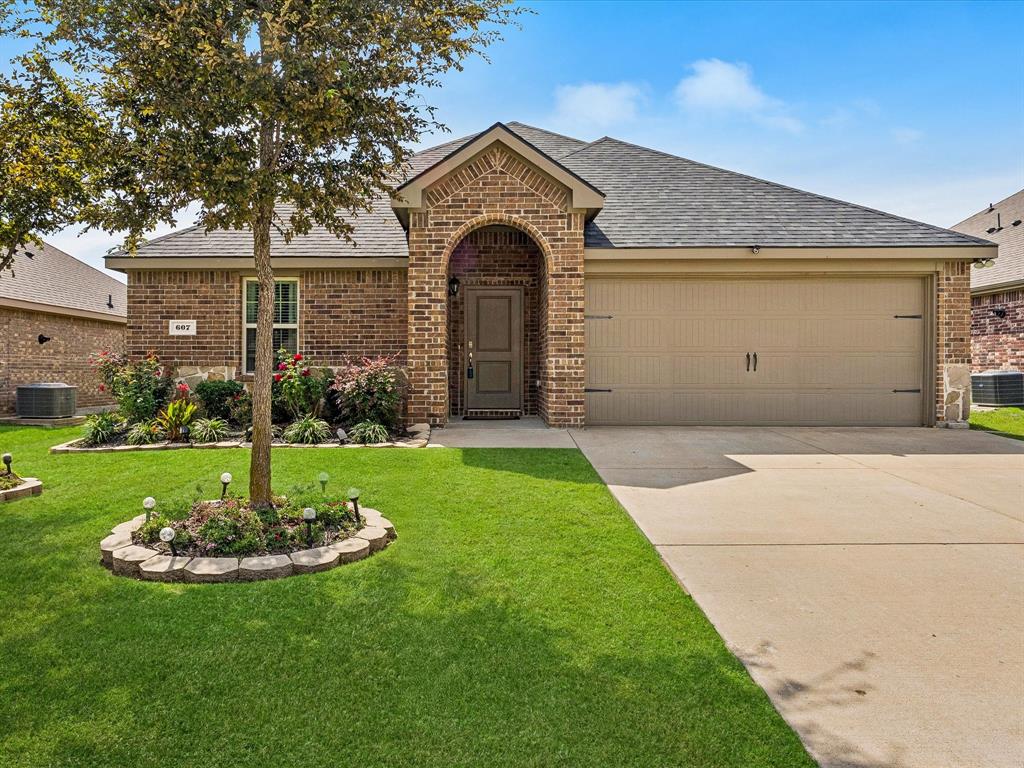 View of front of home with brick siding, a shingled roof, concrete driveway, and a front yard
