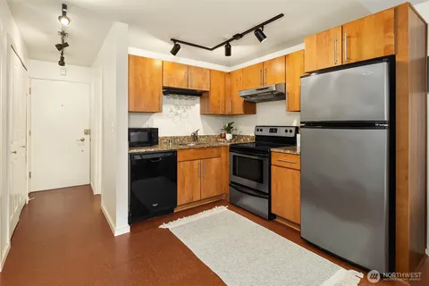a kitchen with stainless steel appliances granite countertop a refrigerator a sink dishwasher a stove with white cabinets and countertops