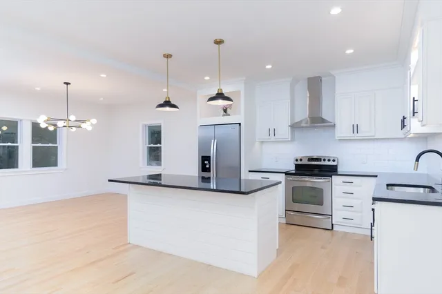 a kitchen with stainless steel appliances granite countertop a sink a stove a refrigerator and white cabinets