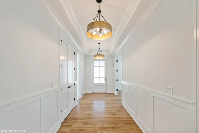 a hallway with wooden floor chandelier and entryway