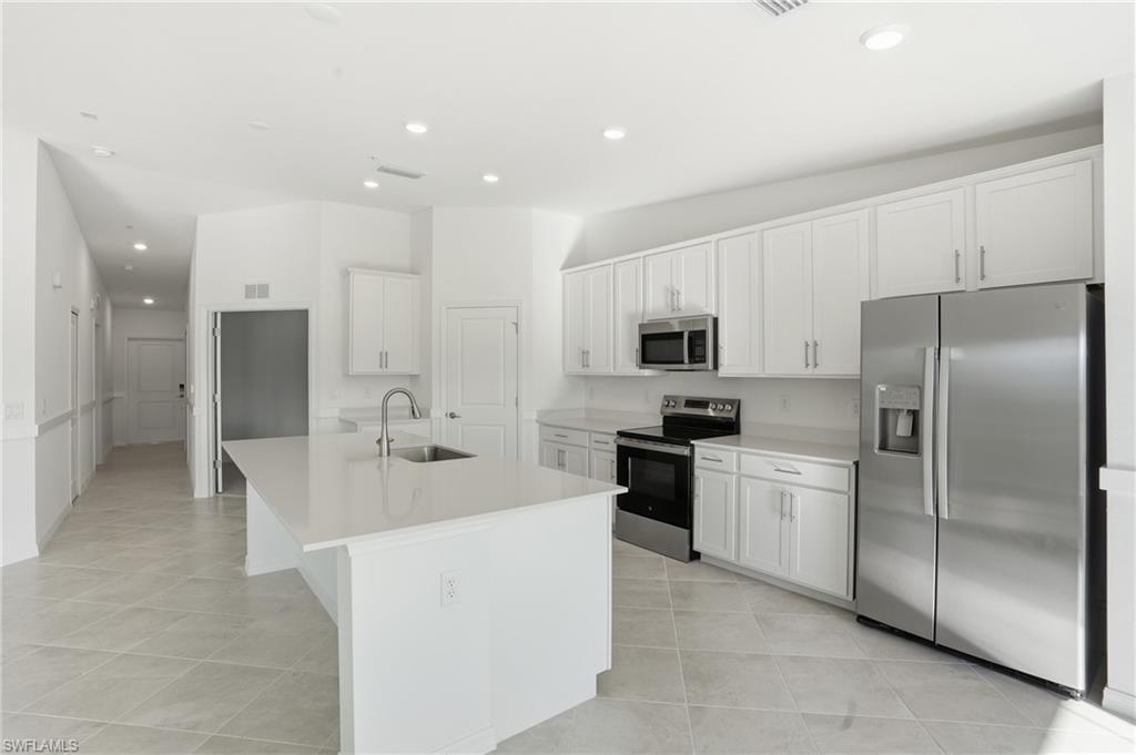 15185 Bluffton Lane, Unit 826 Punta Gorda, FL 33982 - Photo 16 of 50 a large kitchen with stainless steel appliances kitchen island granite countertop a refrigerator a sink a stove and white cabinets