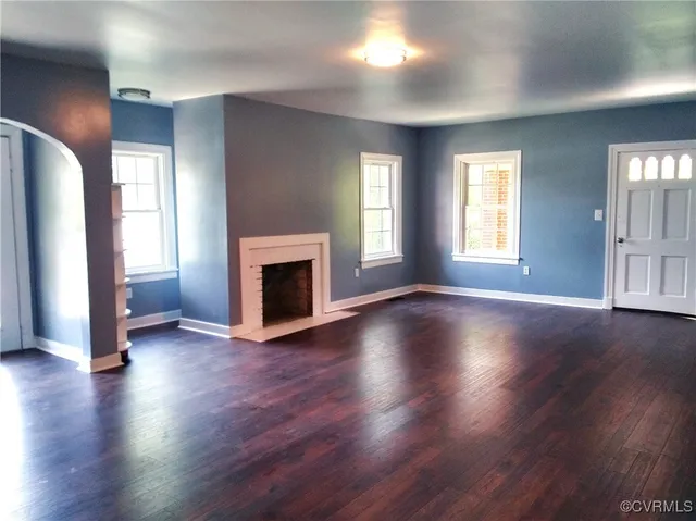 an empty room with wooden floor and a fireplace