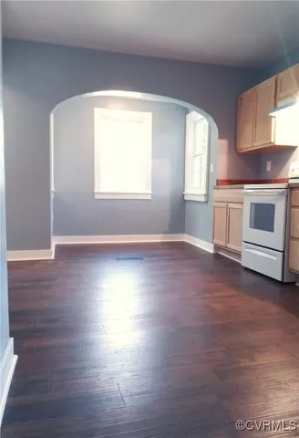 a view of a kitchen and an empty room with wooden floor and a window