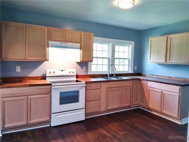 a kitchen with granite countertop wooden cabinets appliances and a window
