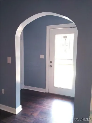 an empty room with wooden floor closet and windows
