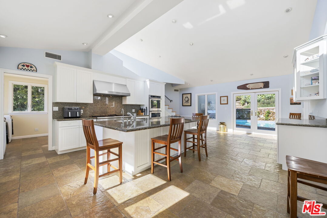 11215 Sunset Boulevard Los Angeles, CA 90049 - Photo 28 of 74 a kitchen with stainless steel appliances kitchen island granite countertop a table and chairs in it