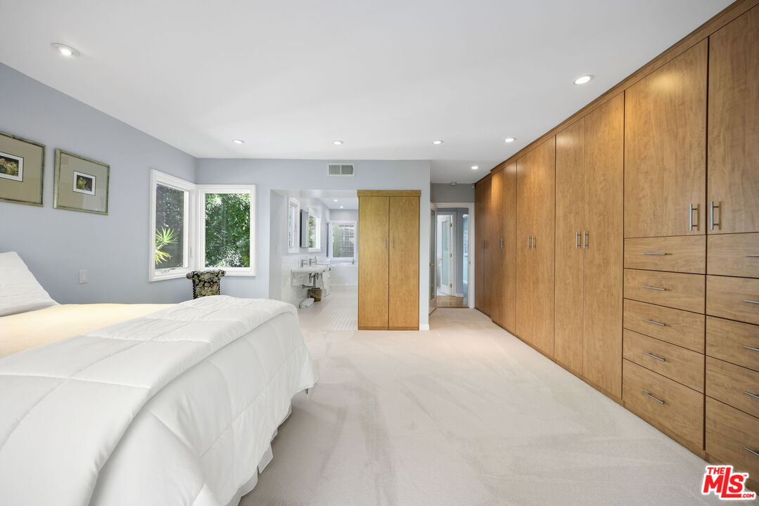 11215 Sunset Boulevard Los Angeles, CA 90049 - Photo 43 of 74 a spacious bedroom with a large bed and a chandelier