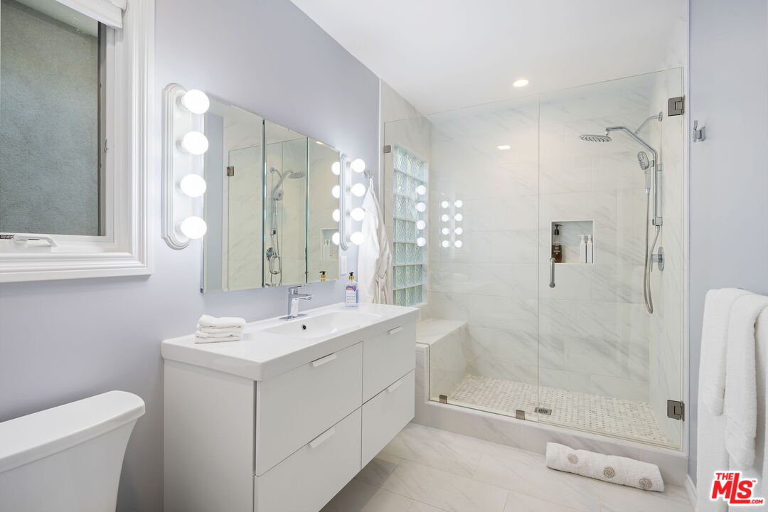 11215 Sunset Boulevard Los Angeles, CA 90049 - Photo 49 of 74 a bathroom with a shower sink and mirror