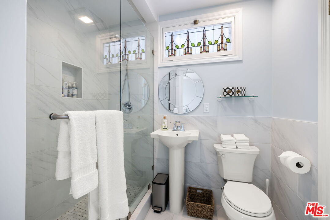 11215 Sunset Boulevard Los Angeles, CA 90049 - Photo 54 of 74 a white toilet sitting next to a bathroom sink and a mirror