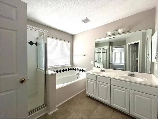 a bathroom with a double vanity sink a mirror a bathtub and next to a window