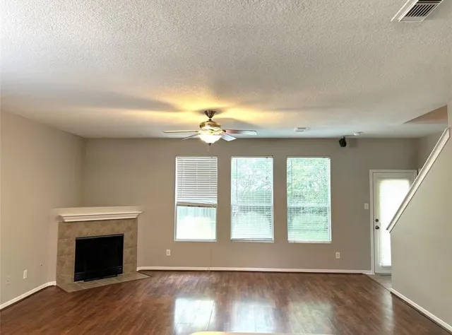 an empty room with wooden floor fireplace and windows