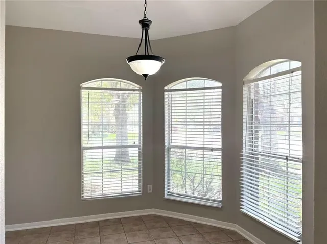 a view of an empty room with windows and chandelier