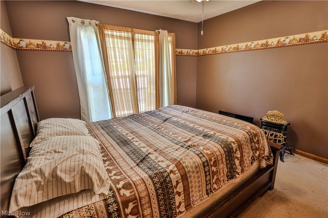 11154 Johnsford Road Southwest Beach City, OH 44608 - Photo 41 of 50 Carpeted bedroom featuring multiple windows with blinds and curtains, a ceiling fan, and a light-colored wall border