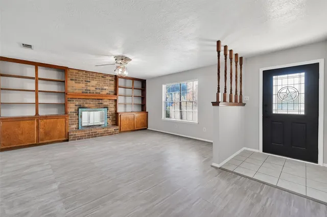 a view of an empty room with a window and fireplace