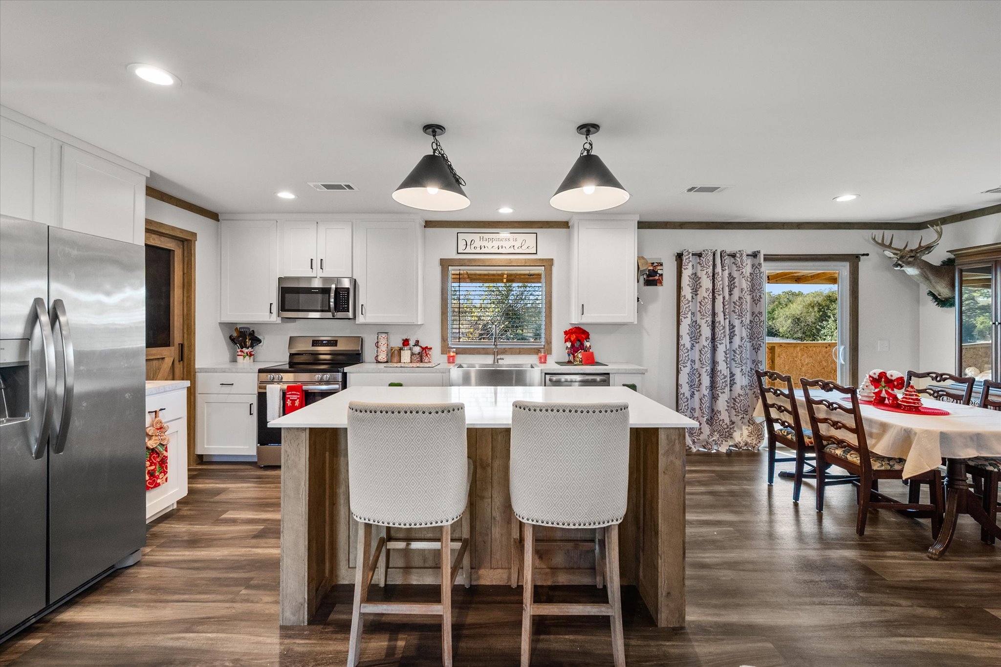16857 Fm 639 Road East Purdon, TX 76679 - Photo 24 of 38 Kitchen featuring appliances with stainless steel finishes, a center island, decorative light fixtures, white cabinetry, and a breakfast bar area