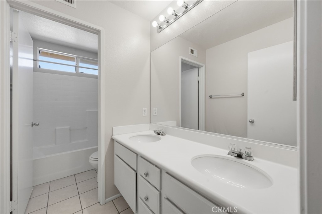 250 Settlers Road Upland, CA 91786 - Photo 22 of 31 a bathroom with a double vanity sink a mirror and a bathtub