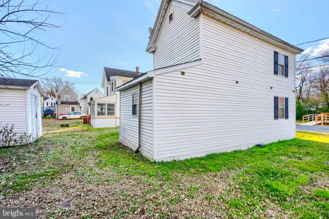 a backyard of a house with lots of plants and large trees