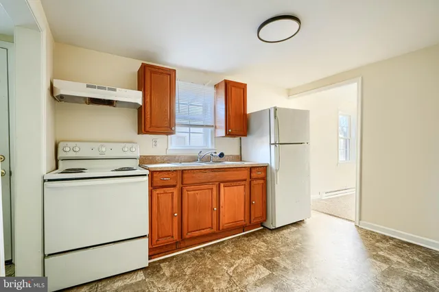 a kitchen with stainless steel appliances granite countertop a refrigerator a sink and white cabinets