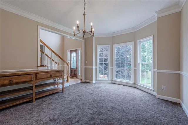 an empty room with chandelier fan and windows