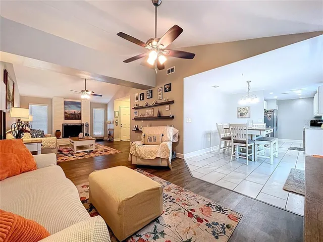 a dining hall with stainless steel appliances kitchen island granite countertop a dining table chairs and a refrigerator