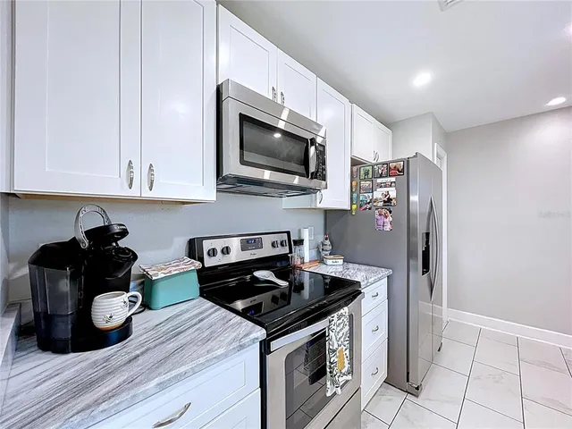 a kitchen with stainless steel appliances a sink a stove a microwave a sink a refrigerator and cabinets