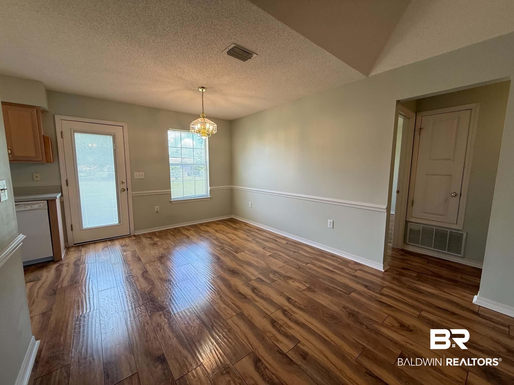 123 Pennbrooke Loop Foley, AL 36535 - Photo 20 of 49 Dining area featuring wood-finish flooring, a vaulted ceiling, and a decorative pendant light fixture