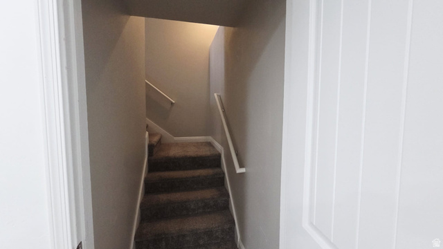 1437 925 South Vernal, UT 84078 - Photo 16 of 47 Carpeted stairway with white handrails and neutral-toned walls