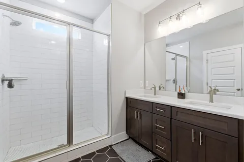 a bathroom with a double vanity sink mirror and shower