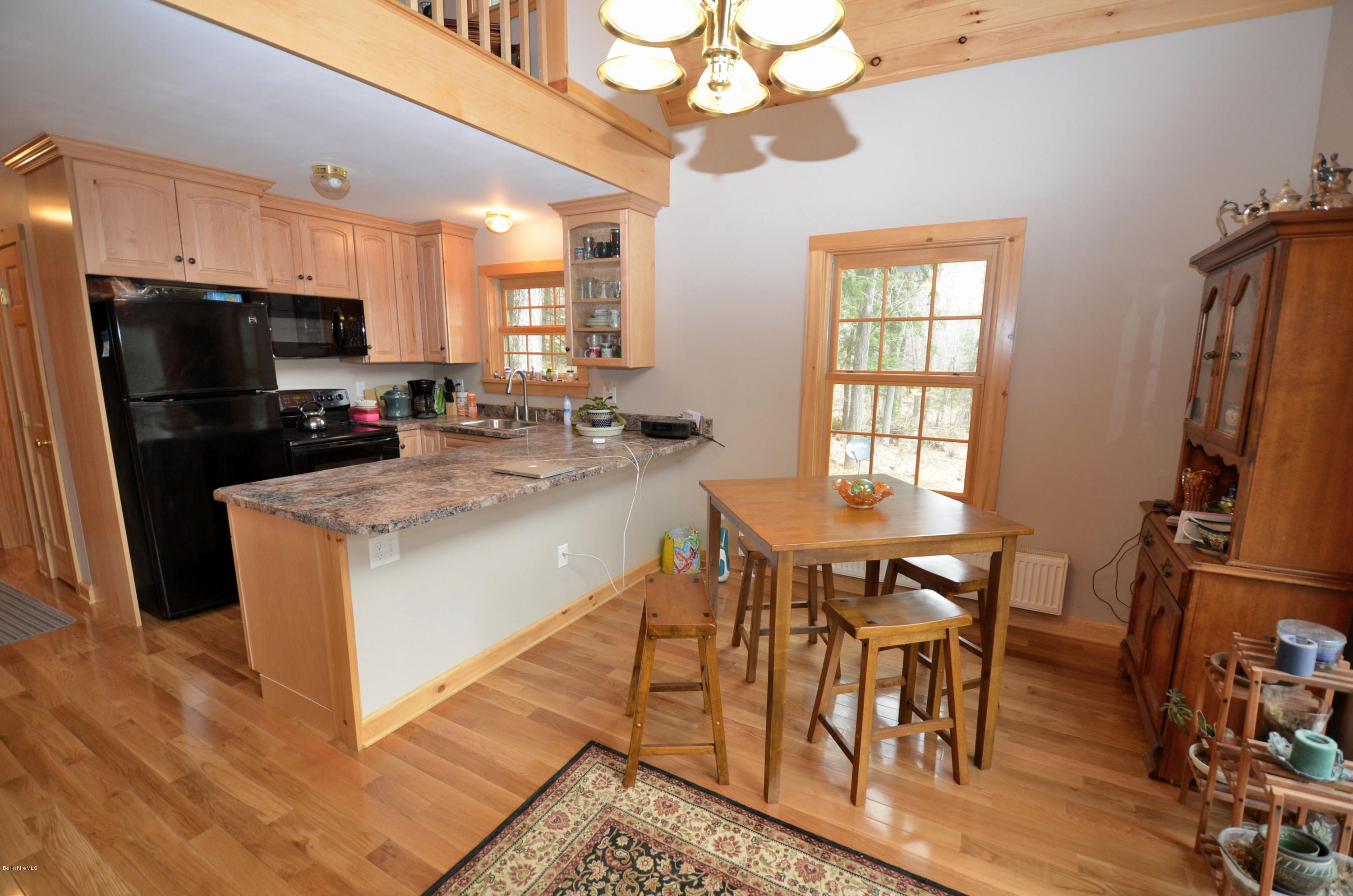 156 Old Pond Road Becket, MA 01223 - Photo 4 of 28 a kitchen with stainless steel appliances granite countertop a stove a refrigerator a sink a dining table and chairs with wooden floor