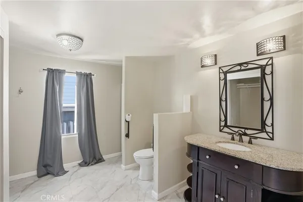 a bathroom with a granite countertop sink a toilet and a mirror