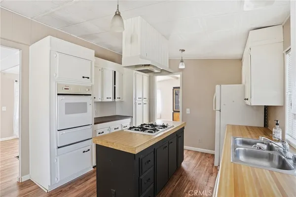 a kitchen with a refrigerator a stove top oven a counter space and wooden floor