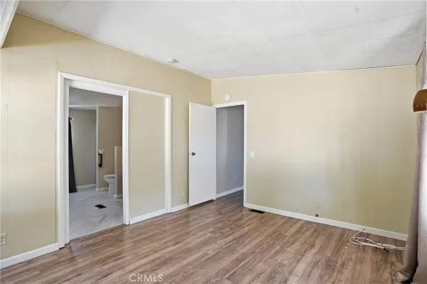 a view of an empty room with wooden floor and closet