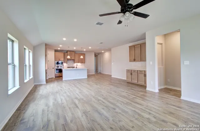 a view of a livingroom with furniture a ceiling fan and wooden floor