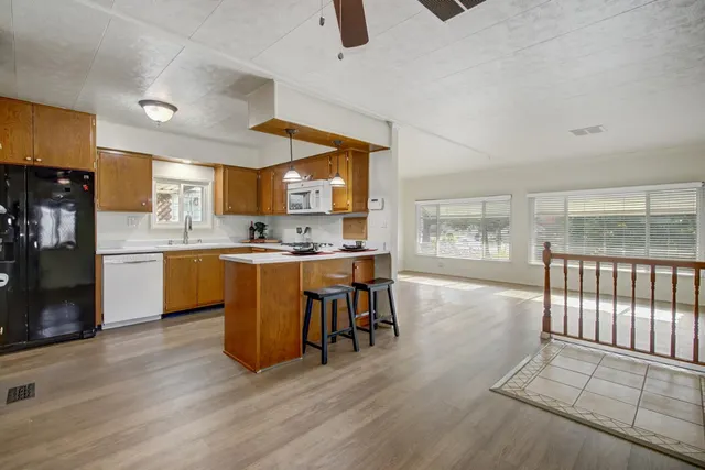 a kitchen with stainless steel appliances granite countertop a stove top oven a sink a dining table and chairs with wooden floor