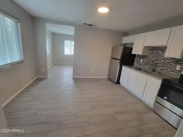 a view of a kitchen with a sink stove cabinets and empty room