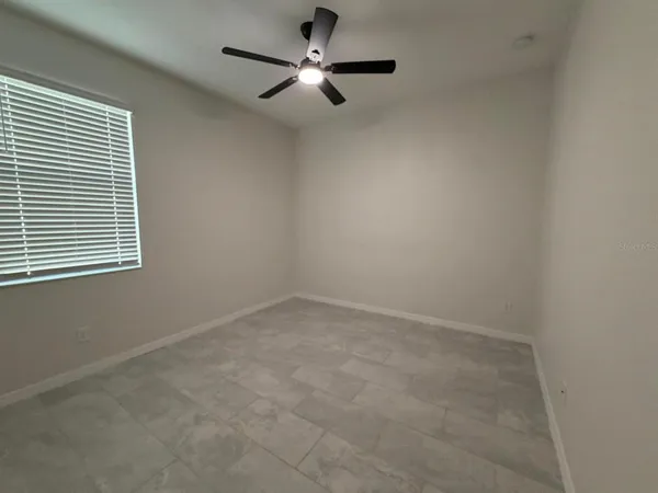 an empty room with a window and a fan