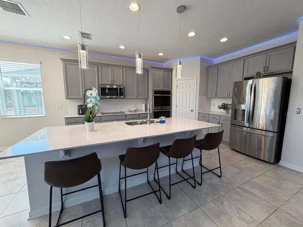 a kitchen with stainless steel appliances kitchen island granite countertop a table chairs microwave and sink