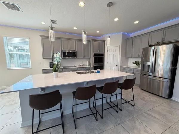 a kitchen with stainless steel appliances kitchen island granite countertop a table chairs and a refrigerator