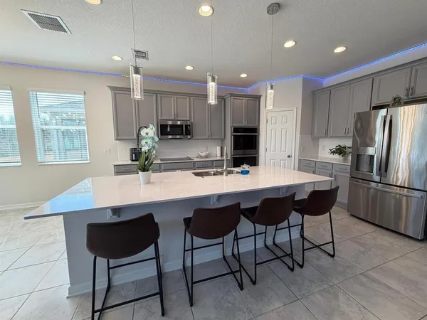 a kitchen with stainless steel appliances kitchen island granite countertop a table chairs and a refrigerator