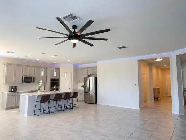 a view of a kitchen with kitchen island stainless steel appliances refrigerator cabinets and furniture