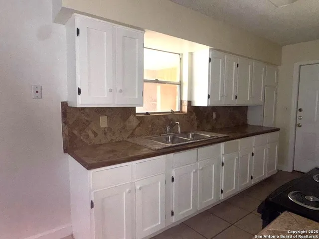 a kitchen with granite countertop white cabinets and black appliances