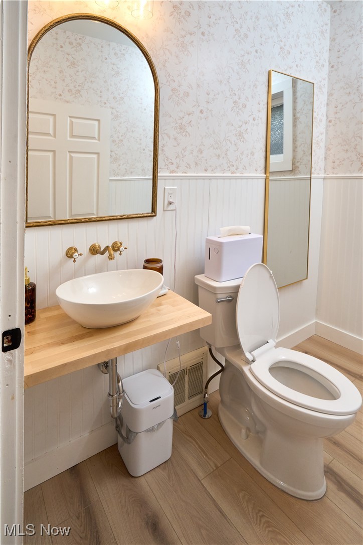 5432 State Road Parma, OH 44134 - Photo 9 of 47 Half bathroom featuring a wainscoted wall, wallpapered walls, and light wood finished floors