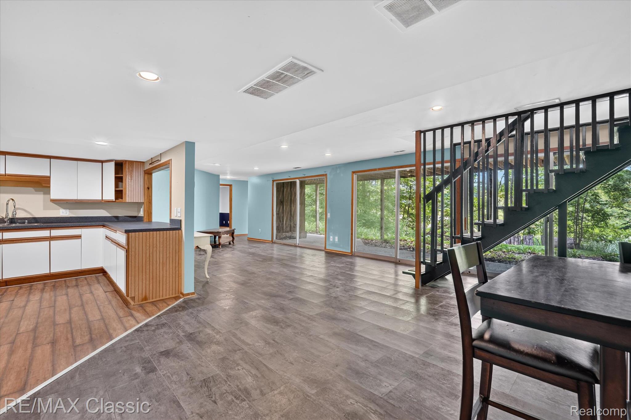 12189 Gage Road Holly, MI 48442 - Photo 33 of 69 Open-concept living area featuring wood-finish flooring, a contemporary staircase with dark wood railings, and multiple sliding glass doors