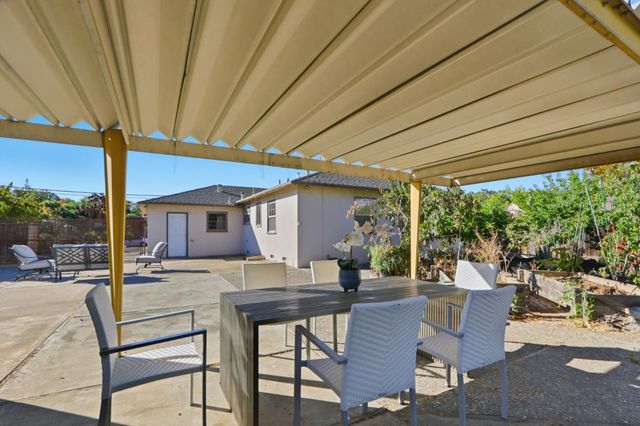 a view of a patio with table and chairs and floor to ceiling window yard