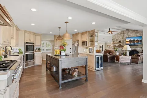a kitchen with stainless steel appliances granite countertop a stove a sink dishwasher and white cabinets with wooden floor