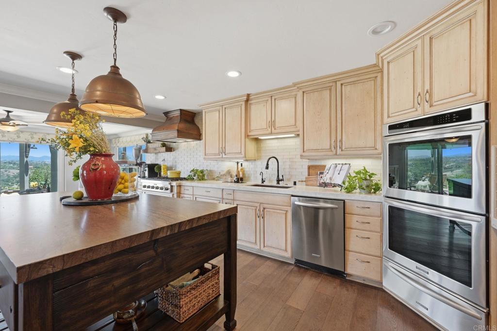 560 Rancho Camino Fallbrook, CA 92028 - Photo 17 of 70 a kitchen with stainless steel appliances granite countertop a stove a sink dishwasher and white cabinets with wooden floor