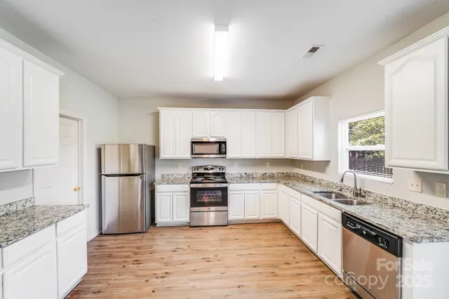 a kitchen with granite countertop a refrigerator stove top oven and sink